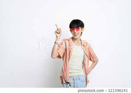 Confident young man wearing sunglasses pointing fingers at copy space over white background 121396241