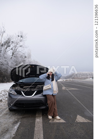 Woman watching at Car Engine on Snowy Roadside Woman watching at Car Engine on Snowy Roadside 121396636