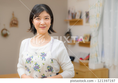 一個可愛的微笑母親做家務，看著鏡頭的形象 121397197
