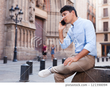 Modern guy walks in city and communicates on smartphone 121398094