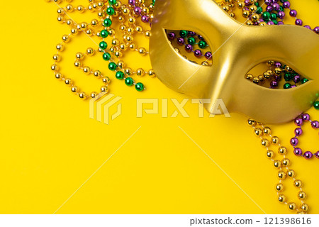Mardi Gras beads and mask on yellow background Mardi Gras beads and mask on yellow background 121398616