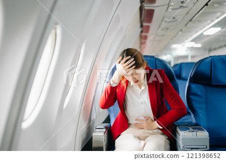 Photo of a frustrated woman sitting on an airplane with her head in her hands. Asian woman sitting 121398652