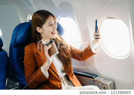 Portrait of a successful Asian businesswoman or entrepreneur in a formal suit on an airplane sitting in business class Portrait of a successful Asian businesswoman or entrepreneur in a formal suit on an airplane sitting in business class 121398805
