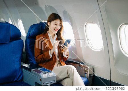Portrait of a successful Asian businesswoman or entrepreneur in a formal suit on an airplane sitting in business class Portrait of a successful Asian businesswoman or entrepreneur in a formal suit on an airplane sitting in business class 121398962