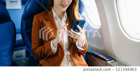 Portrait of a successful Asian businesswoman or entrepreneur in a formal suit on an airplane sitting in business class Portrait of a successful Asian businesswoman or entrepreneur in a formal suit on an airplane sitting in business class 121398963