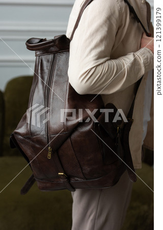 A man posing, with a leather brown backpack 121399179