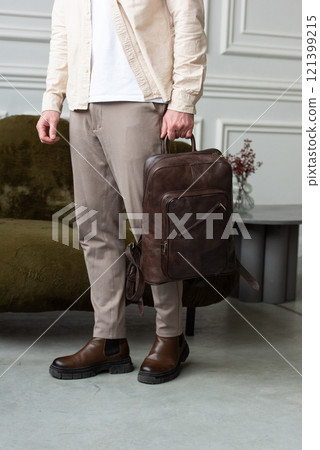 A Stylish and Professional Man Standing with a brown backpack in a Contemporary Modern Setting. 121399215