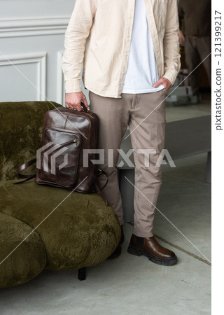 A Stylish and Professional Man Standing with a brown backpack in a Contemporary Modern Setting. 121399217