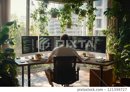 Programmer working with computer at table. Screens show layered code structures and systems analysis. AI Generated. 121399727