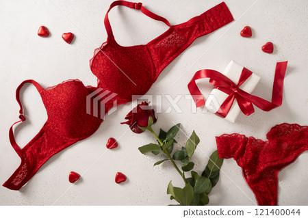 Valentine's day frame with red lace bustier underwear, gift, candy sweets and red roses on white background. Love. View from above. Romantic dating. 121400044