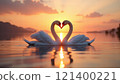 Two swans forming a heart shape at sunset on a lake. 121400221