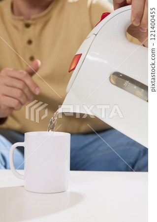 Close up of man pours hot water from kettle to teacup with vitaminizing, mineralizing powder for immunity. 121400455