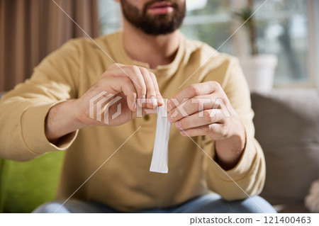 Close-up photo of young man open sachet package with negative space to insert text. Treatment and pharmacy. 121400463