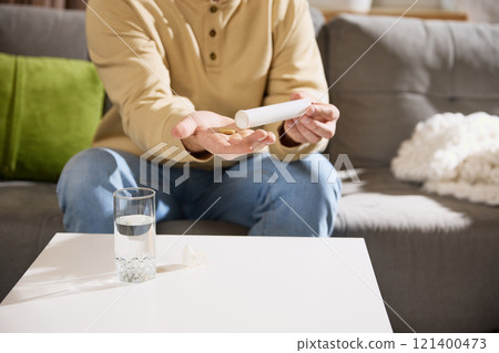 Cropped photo of male model pours soluble tablets with vitamins out of tube with negative space to insert your text. Cropped photo of male model pours soluble tablets with vitamins out of tube with negative space to insert your text. 121400473