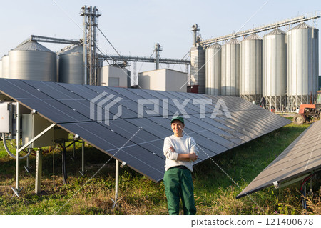 Female farmer with digital tablet on a modern farm using solar panels. Agricultural silos in the background 121400678