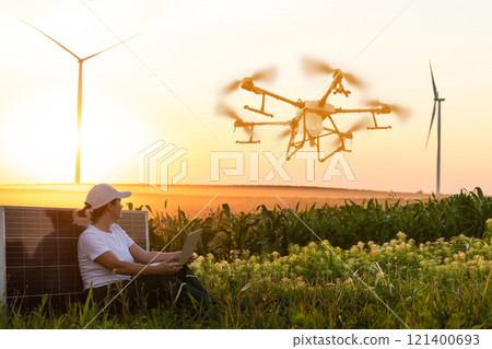 Woman farmer controls drone sprayer with a laptop. Smart farming and precision agriculture 121400693