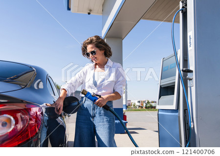Woman holds a hydrogen fueling nozzle on a hydrogen filling station. Refueling car with hydrogen fuel 121400706