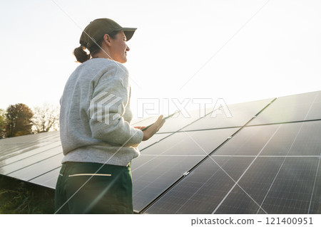 Female farmer with digital tablet on a modern farm using solar panels. 121400951
