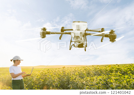 Woman farmer controls drone sprayer with a laptop. Smart farming and precision agriculture Woman farmer controls drone sprayer with a laptop. Smart farming and precision agriculture 121401042