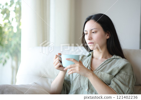 Apathetic asian woman drinking and complaining at home 121402236