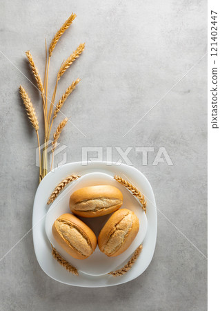 French buns and wheat ears on a marmoreal table. French buns and wheat ears on a marmoreal table. 121402447