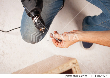 A man holds a screw and a drill in his hand A man holds a screw and a drill in his hand 121402973