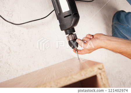 Man twists screw into cupboard Man twists screw into cupboard 121402974