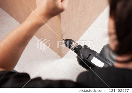 Man twists screw into cupboard 121402977