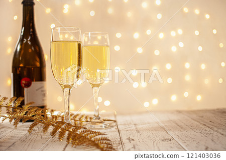 glasses of champagne on a wooden table. The background with a blurred golden garland, sideways. Christmas decorations, background for postcards and congratulations on the New Year. 121403036
