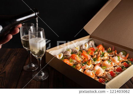 Champagne, tartlets, seafood salads. Cardboard box with food with home delivery. Gift for holiday, party, family dinner. Catering. Delicious snacks. Champagne, tartlets, seafood salads. Cardboard box with food with home delivery. Gift for holiday, party, family dinner. Catering. Delicious snacks. 121403062
