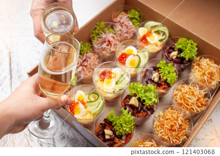 Champagne, tartlets, seafood salads. Cardboard box with food with home delivery. Gift for holiday, party, family dinner. Catering. Delicious snacks. Champagne, tartlets, seafood salads. Cardboard box with food with home delivery. Gift for holiday, party, family dinner. Catering. Delicious snacks. 121403068