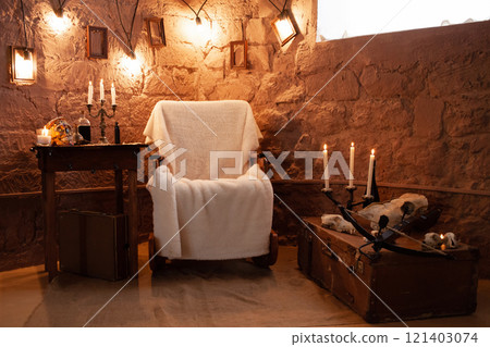 Photo zone in the studio for Halloween. Dramatic intimidating, scenery for All Saints Day celebrations. October 31, photo studio. Armchair, skulls, candles, office, crossbow 121403074