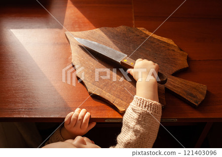 The child pulls a knife from the table. The child can cut, children's home dangers. A little one-year-old girl with a knife. 121403096