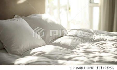 Sunlight illuminating cozy unmade bed with white linens and pillows 121403299