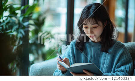 Young woman writing in notebook at coffee shop 121403384