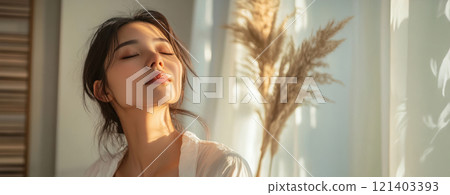 Beautiful young woman enjoying sunlight at home with closed eyes Beautiful young woman enjoying sunlight at home with closed eyes 121403393