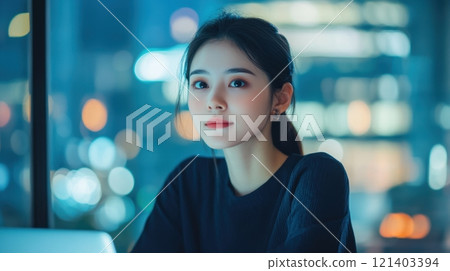 Young businesswoman working late at night in office with city lights in background Young businesswoman working late at night in office with city lights in background 121403394