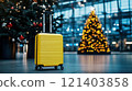 Yellow suitcase stands in airport terminal with christmas trees celebrating holiday season 121403858