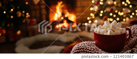 Red mug full of marshmallows warming near fireplace and christmas tree lights 121403867
