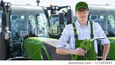 Man with biofuel refueling nozzle next to agricultural machines Man with biofuel refueling nozzle next to agricultural machines 121405647