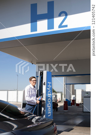 Man holds a hydrogen fueling nozzle on a hydrogen filling station. Refueling car with hydrogen fuel 121405742