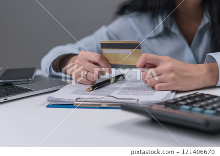 Woman holding credit card and reviewing documents, representing credit approval or financial transactions. Woman holding credit card and reviewing documents, representing credit approval or financial transactions. 121406670