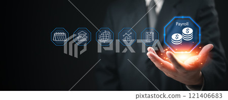 Businessman presenting a glowing payroll icon with financial system icons floating in the air. 121406683