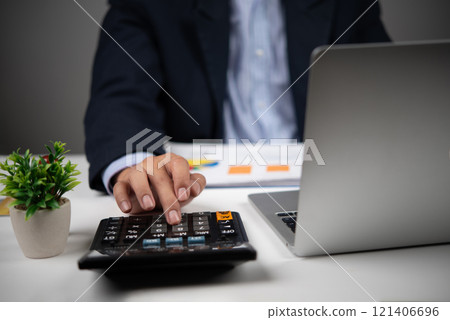 A businessman uses a calculator to perform financial calculations or budget planning. 121406696