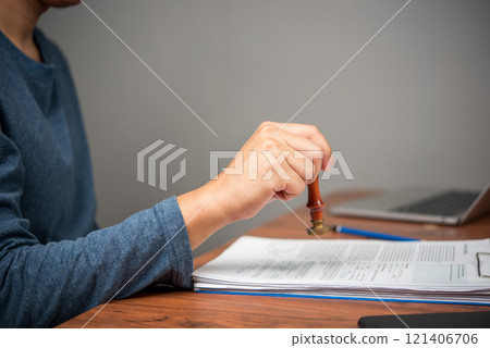 A hand stamps documents with a traditional wax seal for verification. 121406706