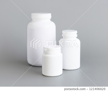 White plastic pill bottles closeup against grey, mockup. Healthcare concept, herbal supplements 121406820