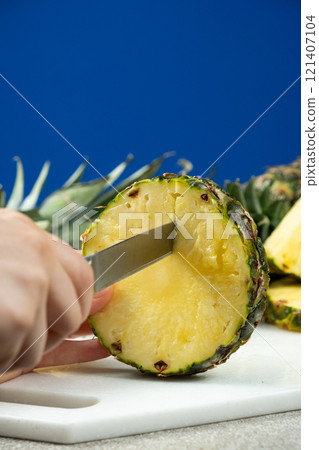 Hands cutting fresh pineapple fruit into pieces. 121407104