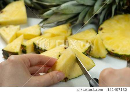 Hands cutting fresh pineapple fruit into pieces. 121407180