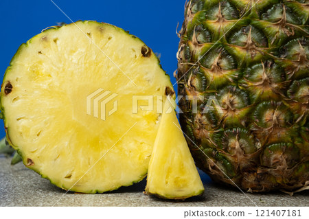 Slice of pineapple and whole pineapple on blue background close-up. 121407181