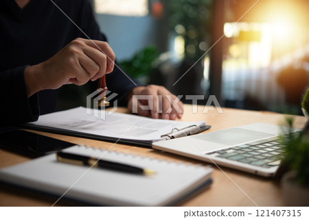 Man stamping approval on financial, banking, or investment documents at his desk official paperwork. rubber stamp with contract law and business documentation for legal agreements financial Man stamping approval on financial, banking, or investment documents at his desk official paperwork. rubber stamp with contract law and business documentation for legal agreements financial 121407315
